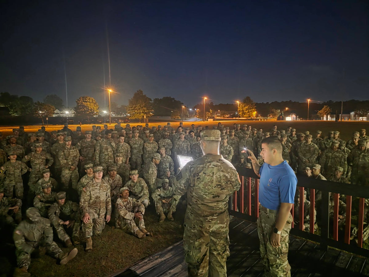 Group of soldiers meet at night for instructions on beginning their ruck.